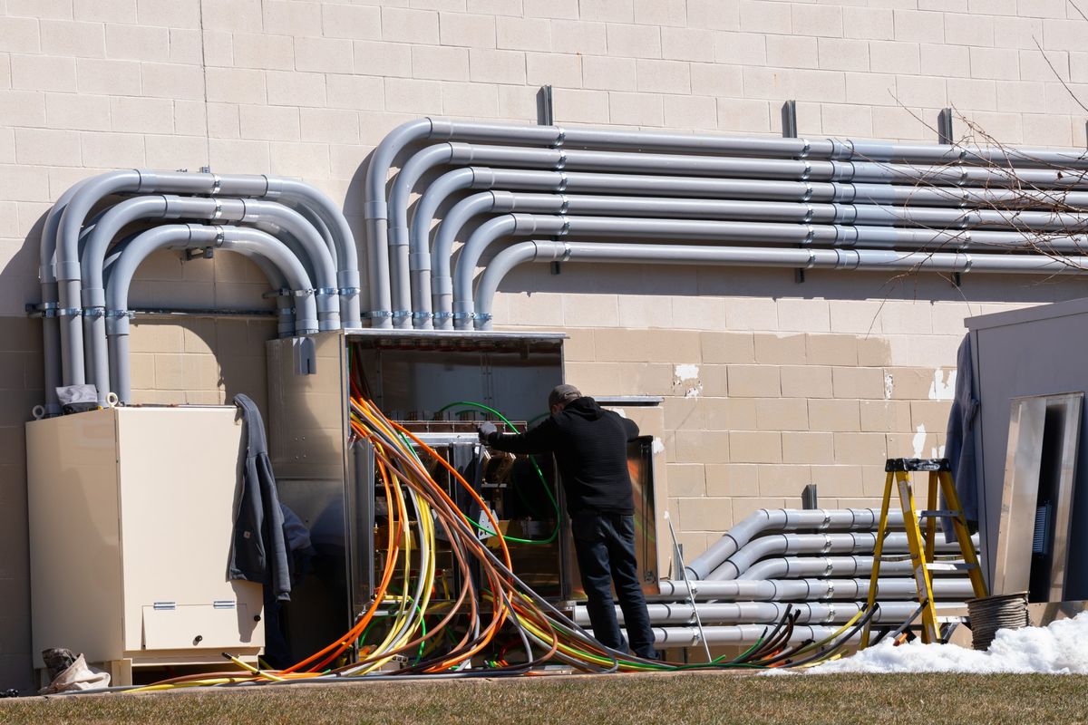 Electrician connecting new service conductors in an outdoor electrical service cabinet