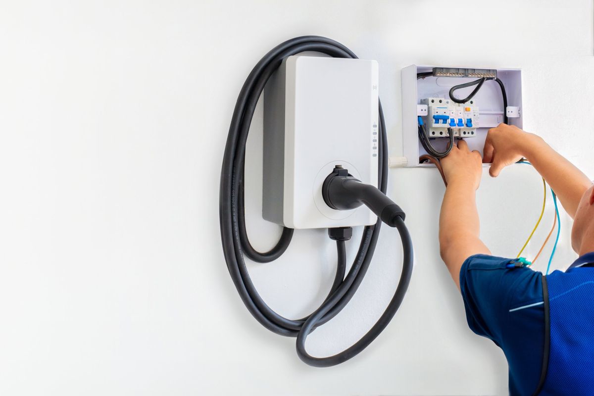 Electrician wiring the breaker for a new wall-mounted EV charger