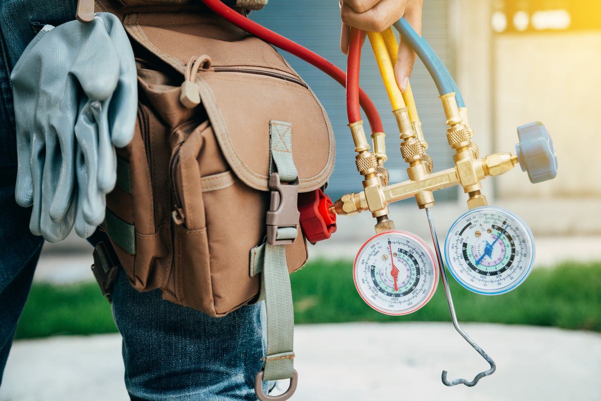 HVAC technician holding a refrigerant manifold gauge set with red, yellow and blue hoses